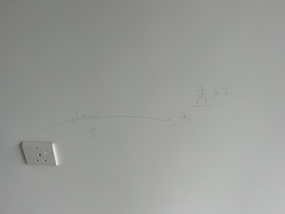 Wall with pencil markings and an electrical outlet.
