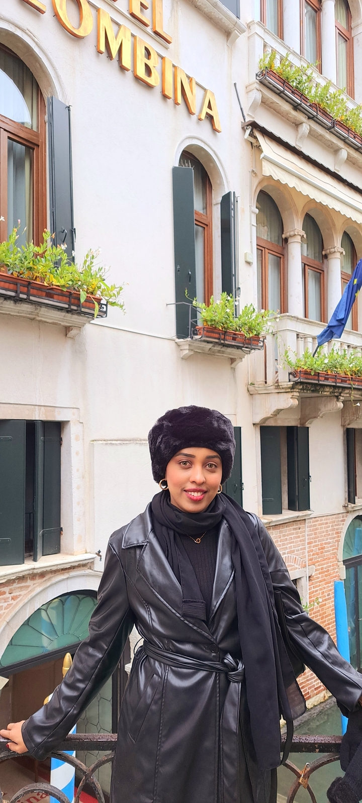 Eine Person, die vor einem Gebäude mit Blumenkästen steht.