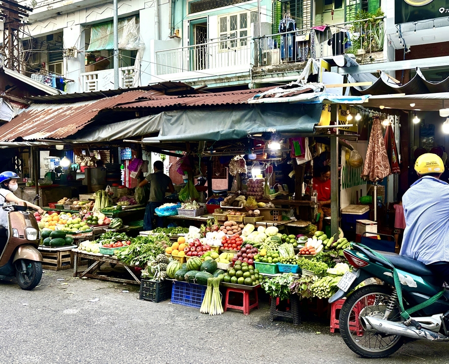 Marché de rue animé avec divers fruits et légumes.
