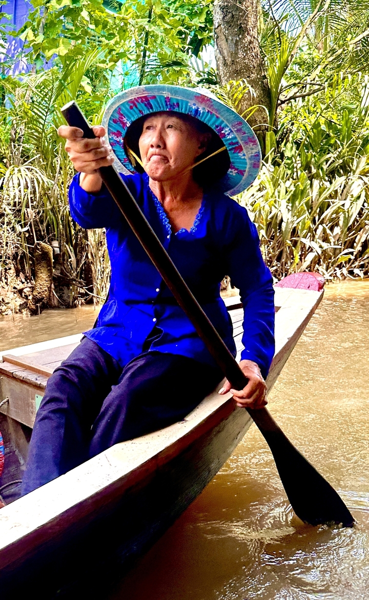 Personne pagayant dans un petit bateau en bois.