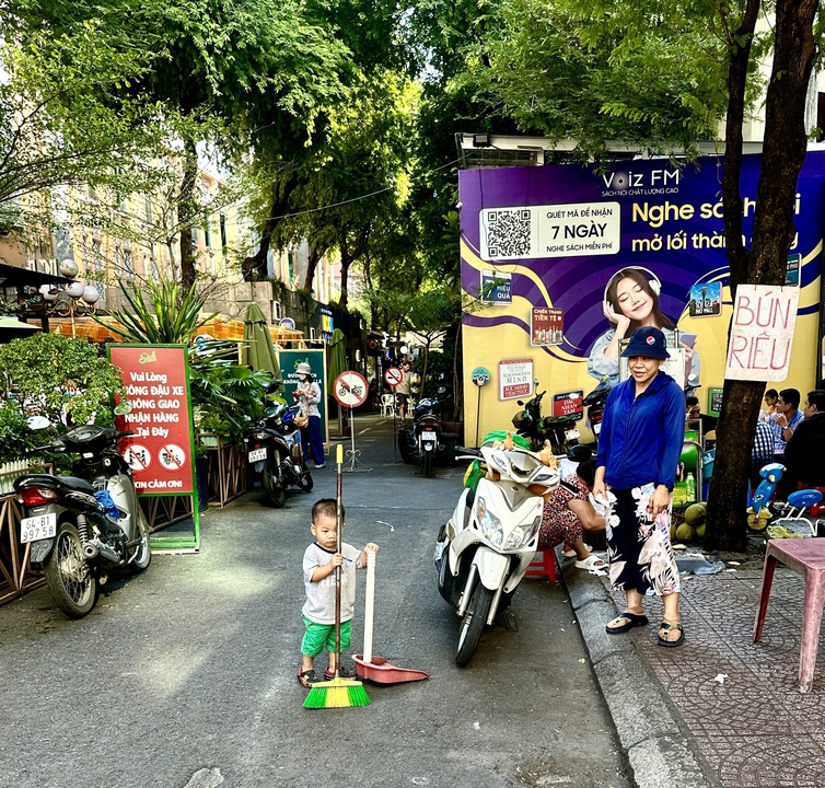 Des gens qui marchent près de scooters garés et de panneaux de signalisation.