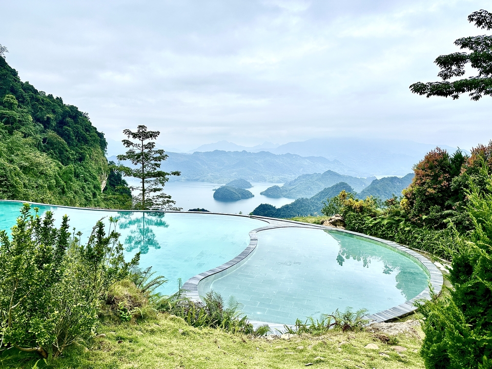 Piscine à débordement avec vue sur une baie pittoresque aux collines verdoyantes.