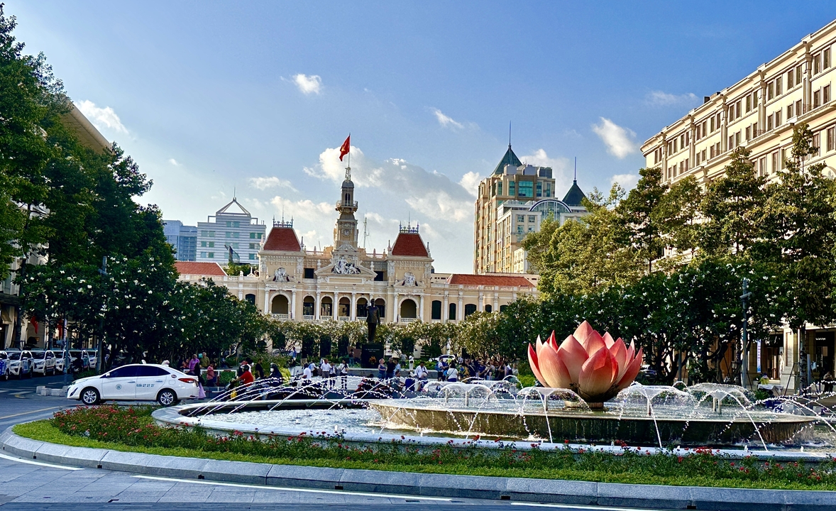 Place de la ville avec une fontaine et un bâtiment historique en arrière-plan.