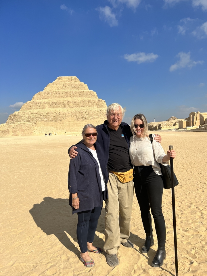 Trois personnes debout devant une pyramide.