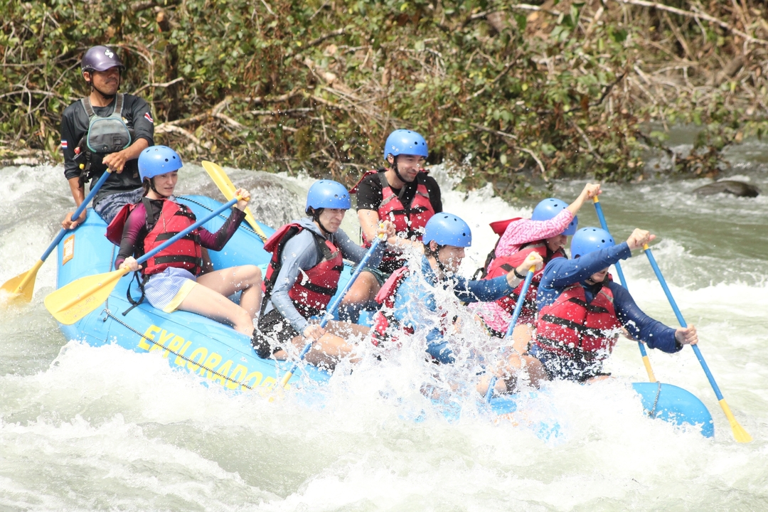 Groupe excité descendant les rapides en rafting avec casques et gilets de sauvetage.