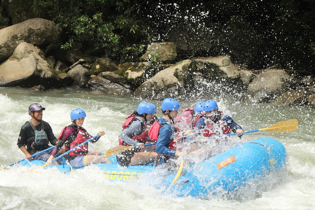 Groupe de personnes faisant du rafting en eau vive dans une rivière.