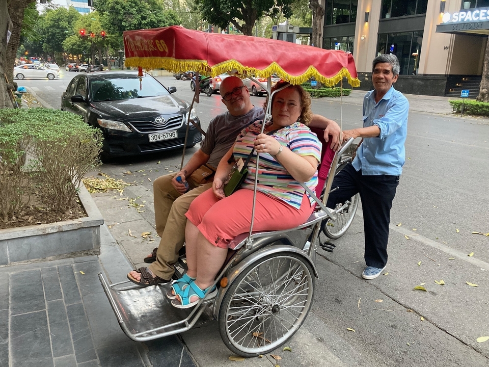 Trois personnes dans un cyclo-pousse dans une rue urbaine.