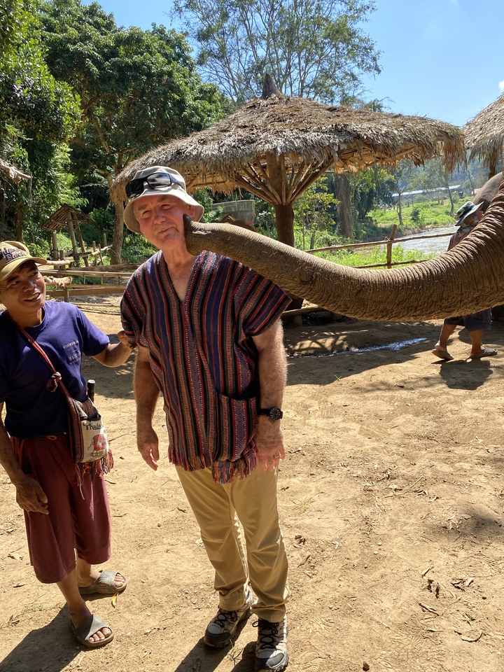 Homme interagissant avec un éléphant dans un sanctuaire.