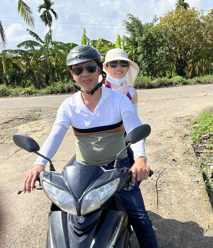 Deux personnes sur un scooter sur une route rurale.