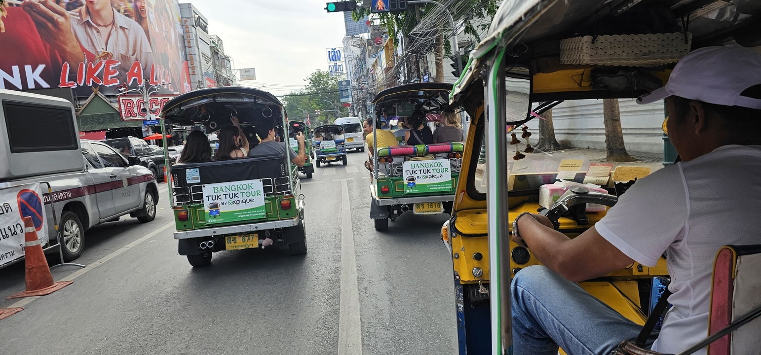 Des tuk-tuks circulant dans une rue animée de Bangkok.