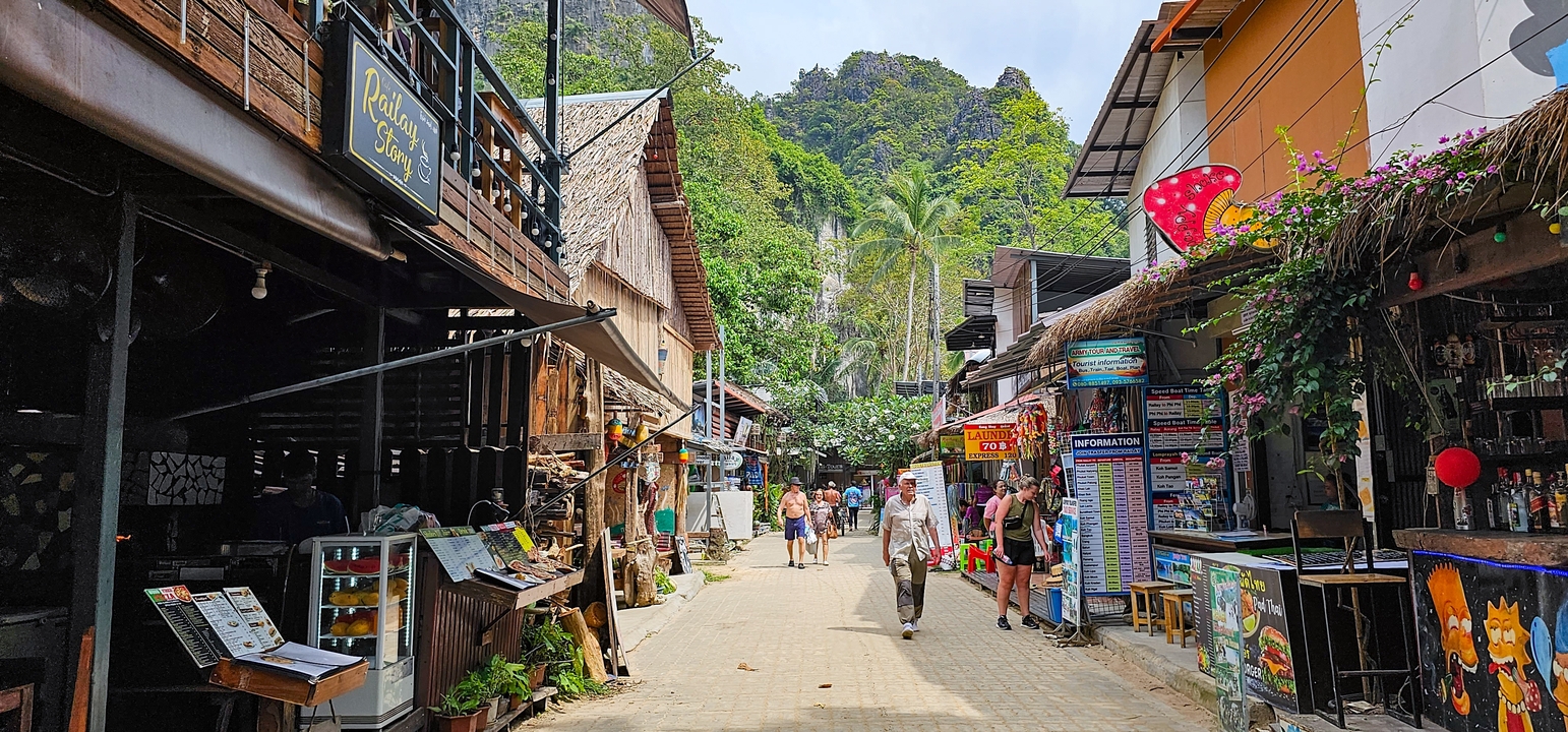 Des gens qui marchent dans une rue commerçante animée avec un paysage montagneux en arrière-plan.