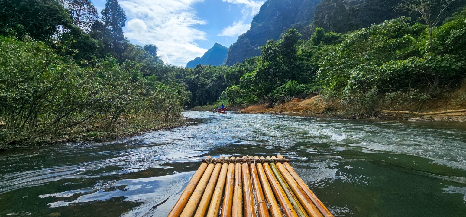 Radeau de bambou sur une rivière avec un arrière-plan montagneux.