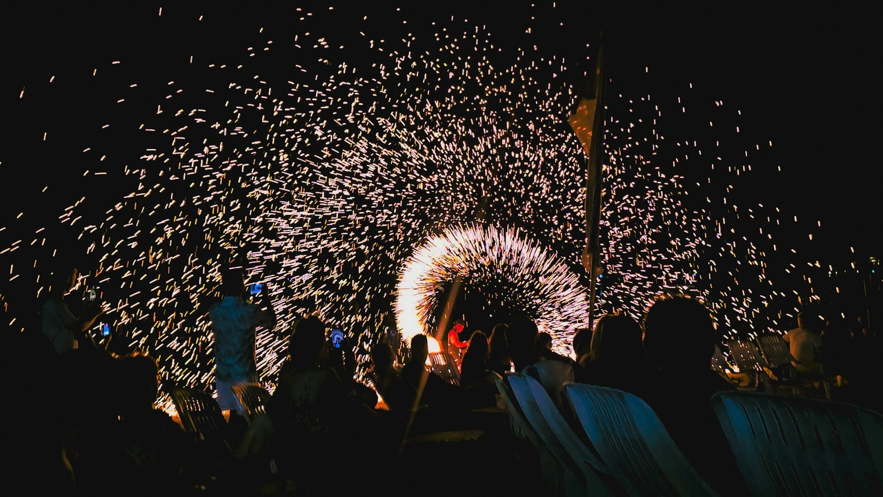 Des gens regardant un feu d'artifice la nuit.