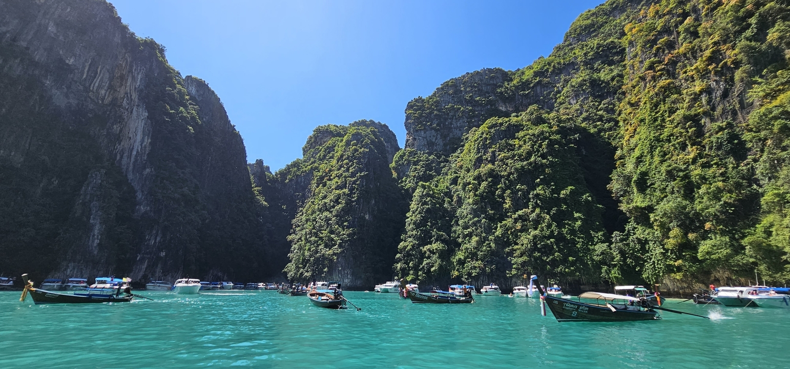 Bateaux et touristes dans des eaux turquoise entourés de falaises calcaires.