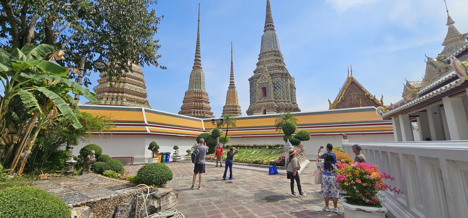 Des touristes explorant un complexe de temples aux flèches colorées.