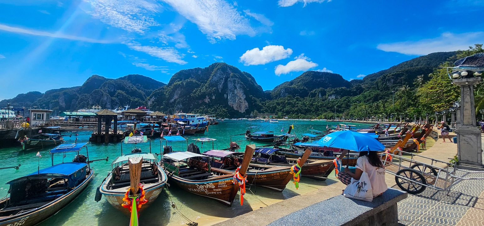 Bateaux colorés amarrés dans des eaux claires entourés de montagnes insulaires.