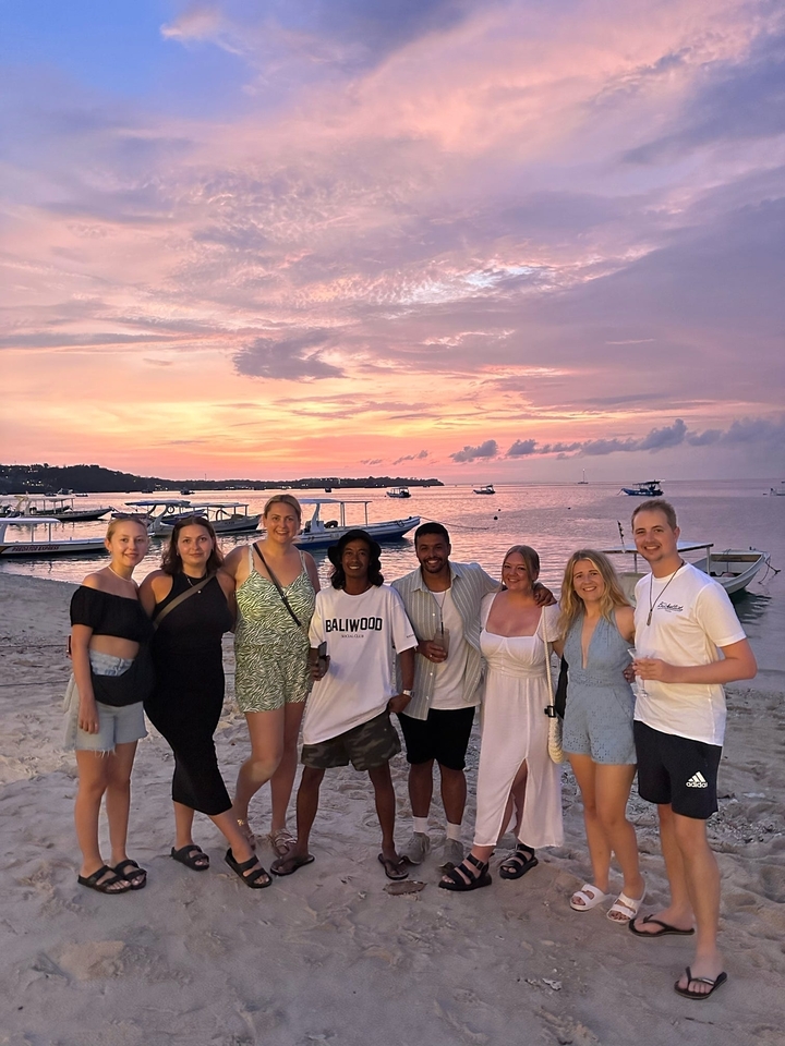 Groupe de personnes posant sur une plage au coucher du soleil.