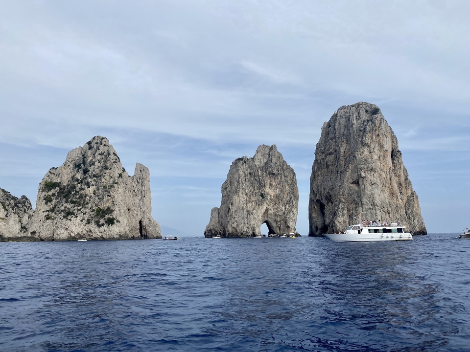 Formations rocheuses en mer avec des bateaux à proximité.