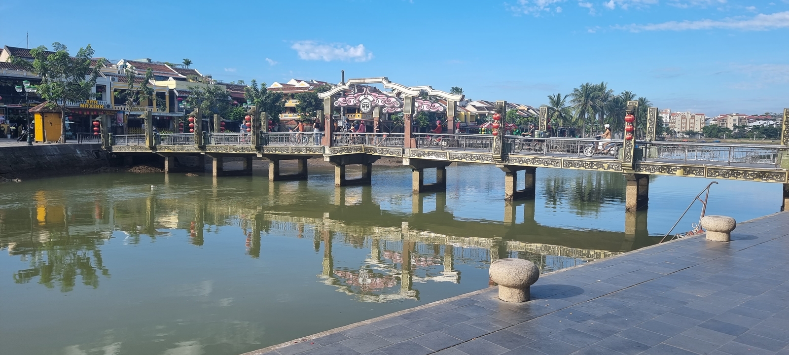 Pont se reflétant dans une rivière dans une ville à l'architecture coloniale.