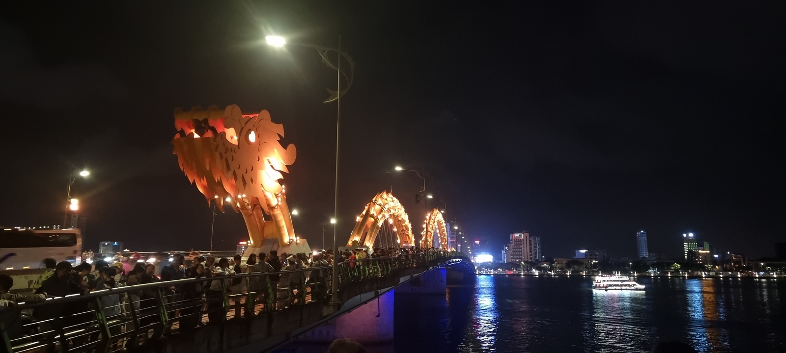 Pont du dragon illuminé la nuit avec une foule de gens.