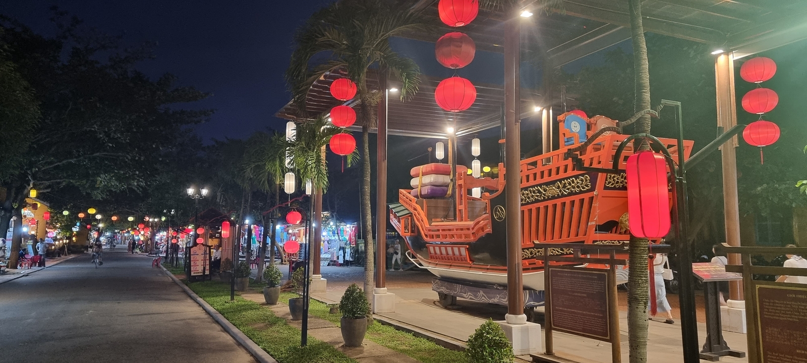 Une rue animée décorée de lanternes la nuit.