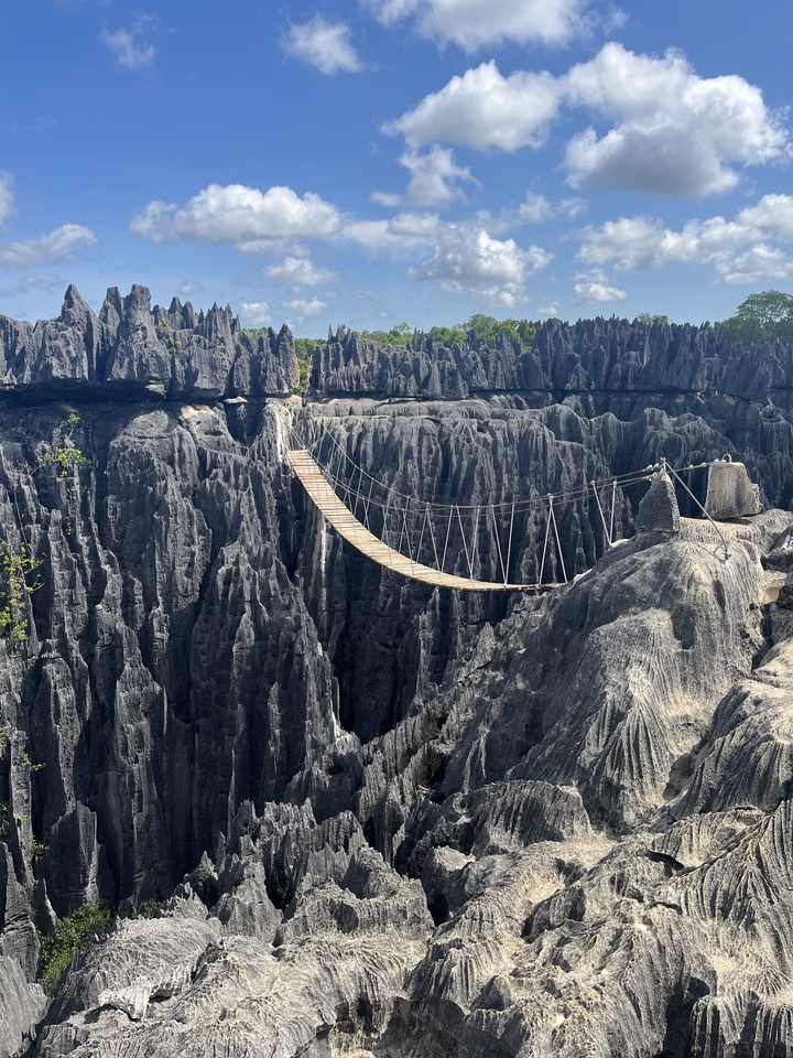 Un pont de corde au-dessus de formations calcaires accidentées.