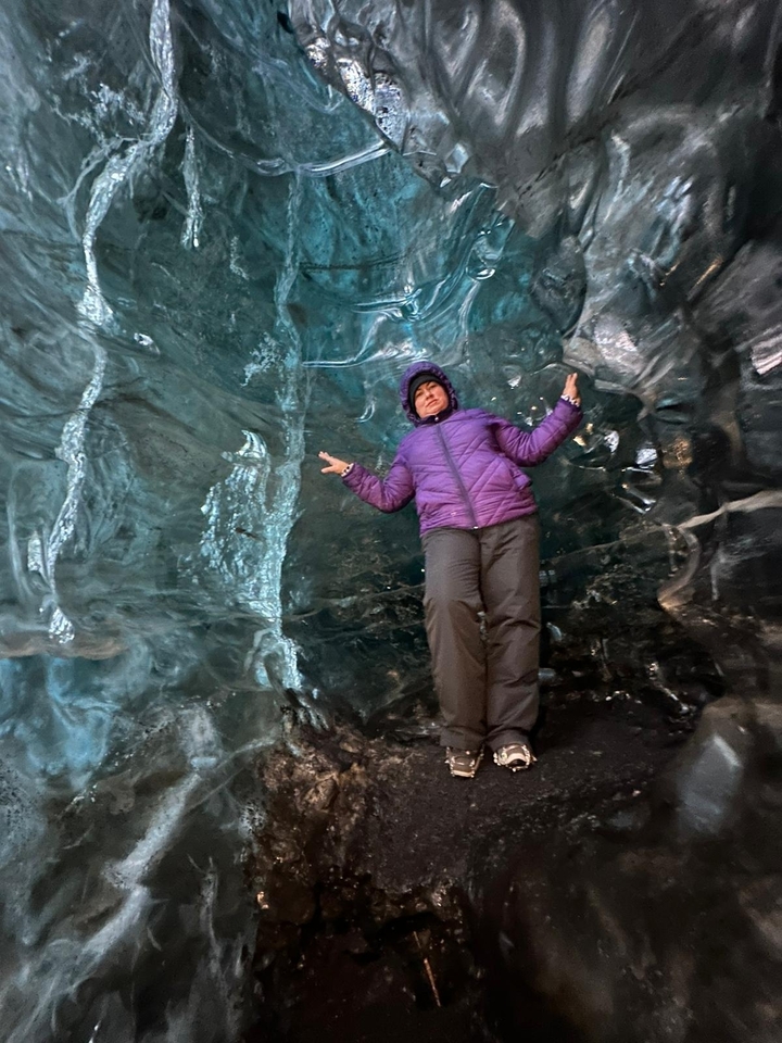 Personne qui pose à l'intérieur d'une grotte de glace bleue.