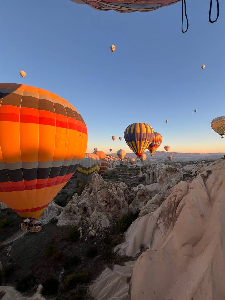 Montgolfières s'élevant dans le ciel au-dessus d'un paysage rocheux.