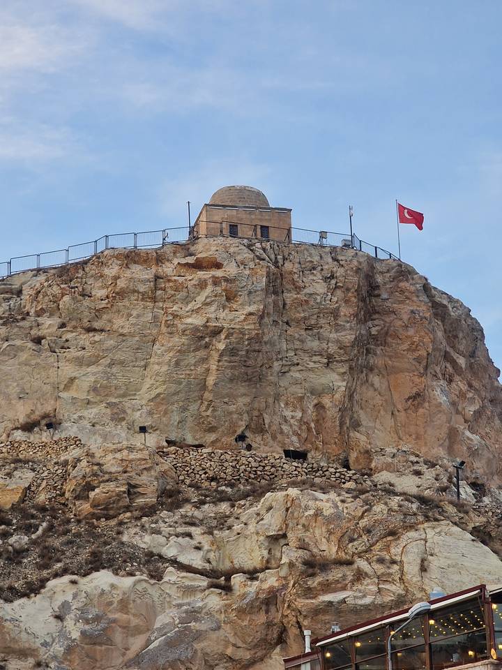 Une forteresse construite dans une colline rocheuse avec un drapeau turc qui flotte.