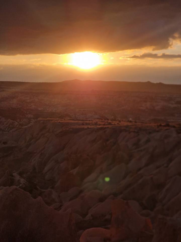 Vue du coucher de soleil sur un paysage accidenté avec des formations rocheuses.
