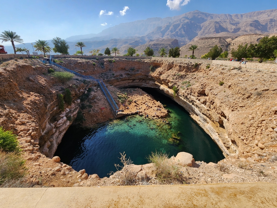 Natural sinkhole surrounded by rocky terrain and greenery.