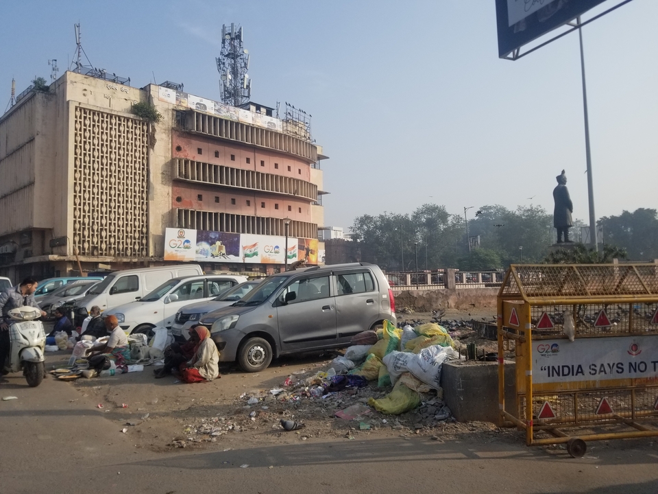 Scène urbaine avec des détritus et des personnes devant un bâtiment.