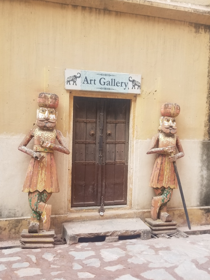 Entrée en bois avec des statues traditionnelles de chaque côté.