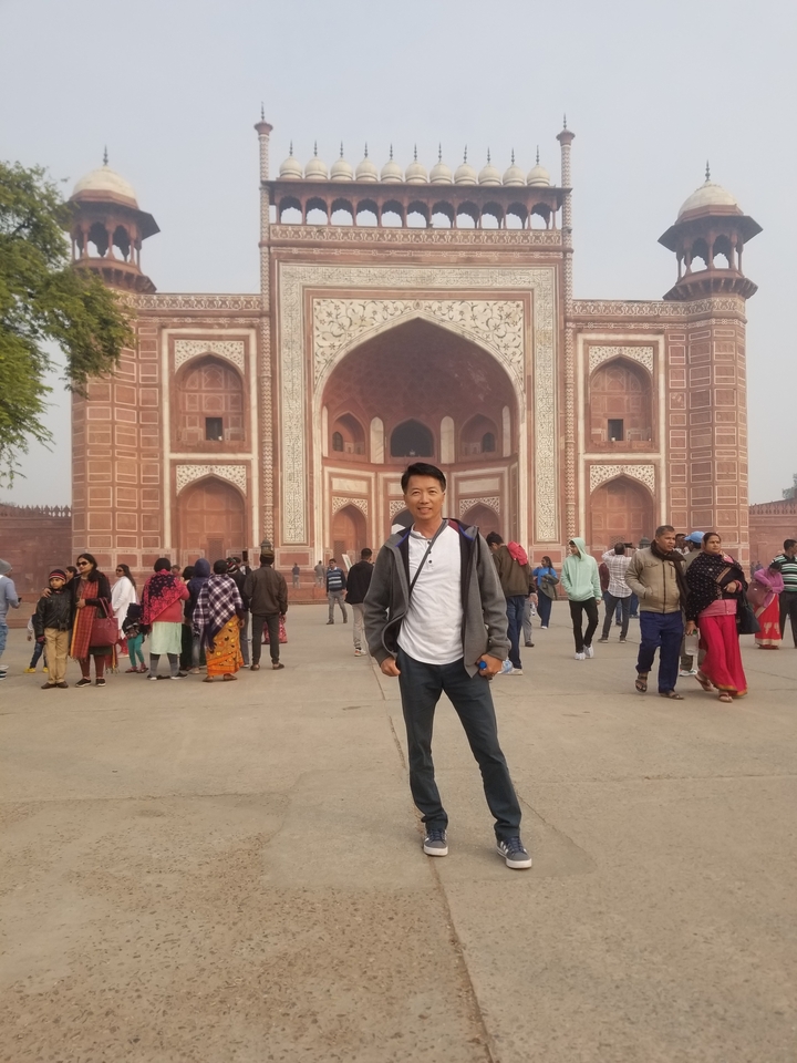 Des touristes debout devant une grande porte historique.