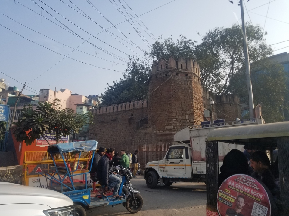 Scène de rue avec mur de pierre historique et personnes.