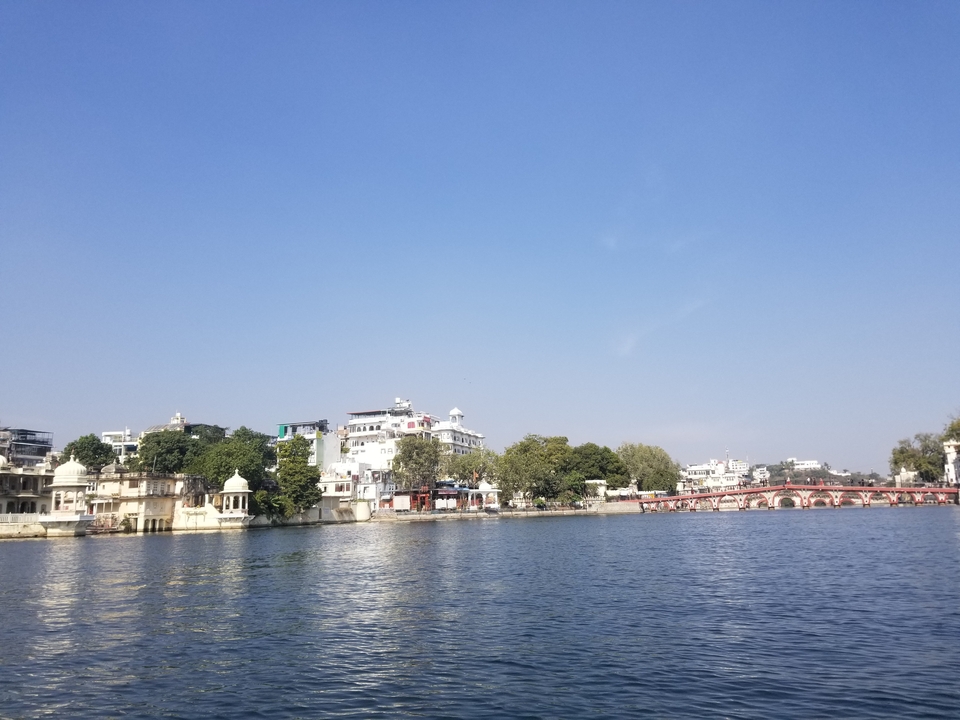 Vue au bord du lac avec des bâtiments urbains et un ciel dégagé.