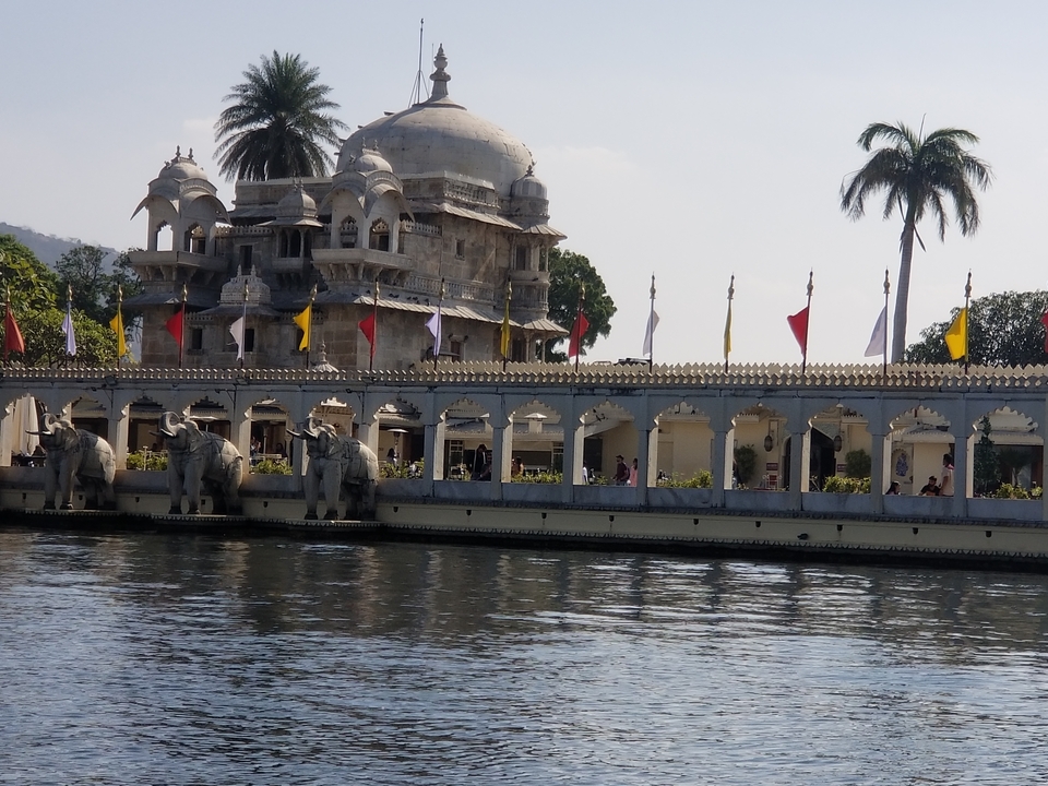 Vue pittoresque d'un palais au bord du lac avec des statues d'éléphants.