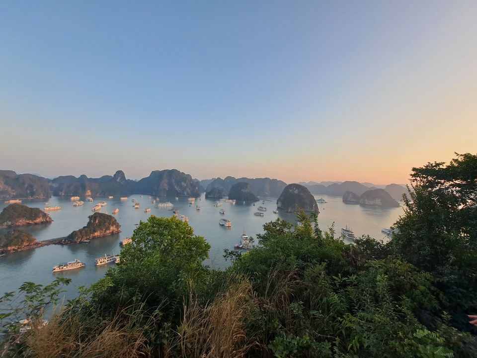 Une vue panoramique de la baie d'Halong avec des bateaux parmi les îles calcaires.