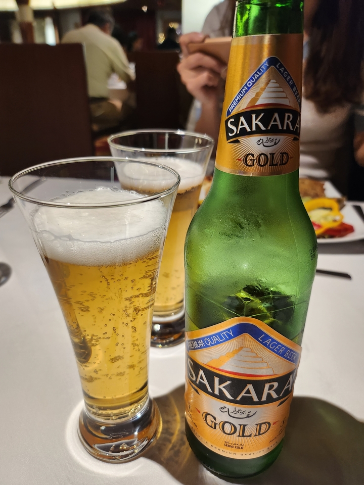 Verre de bière avec une bouteille sur une table.