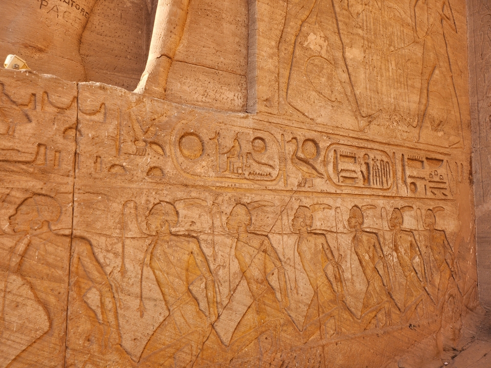 Sculptures détaillées de personnages égyptiens sur un mur de pierre.