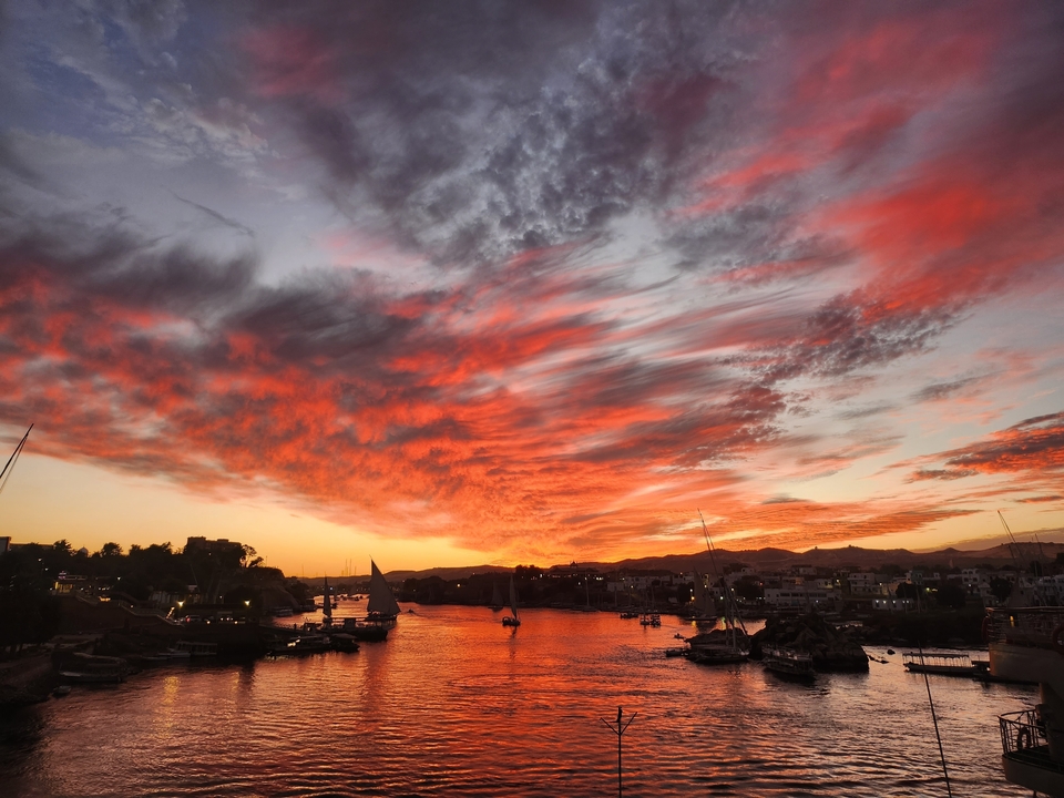 Magnifique coucher de soleil au-dessus d'une rivière avec des bateaux en silhouette contre un ciel coloré.