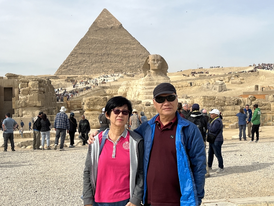 Des touristes posant avec le Sphinx et une pyramide en arrière-plan.
