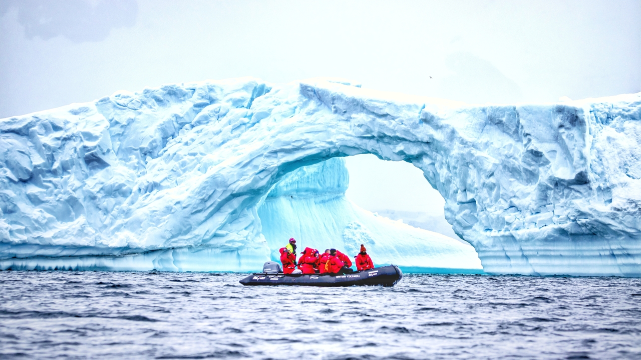 Groupe de personnes sur un petit bateau près de formations de glace saisissantes.
