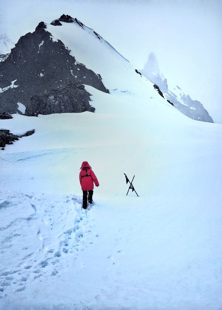 Personne marchant à travers un paysage enneigé avec des montagnes.