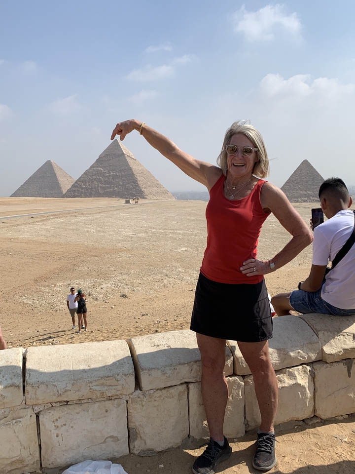 Personne posant avec les pyramides à l'arrière-plan.