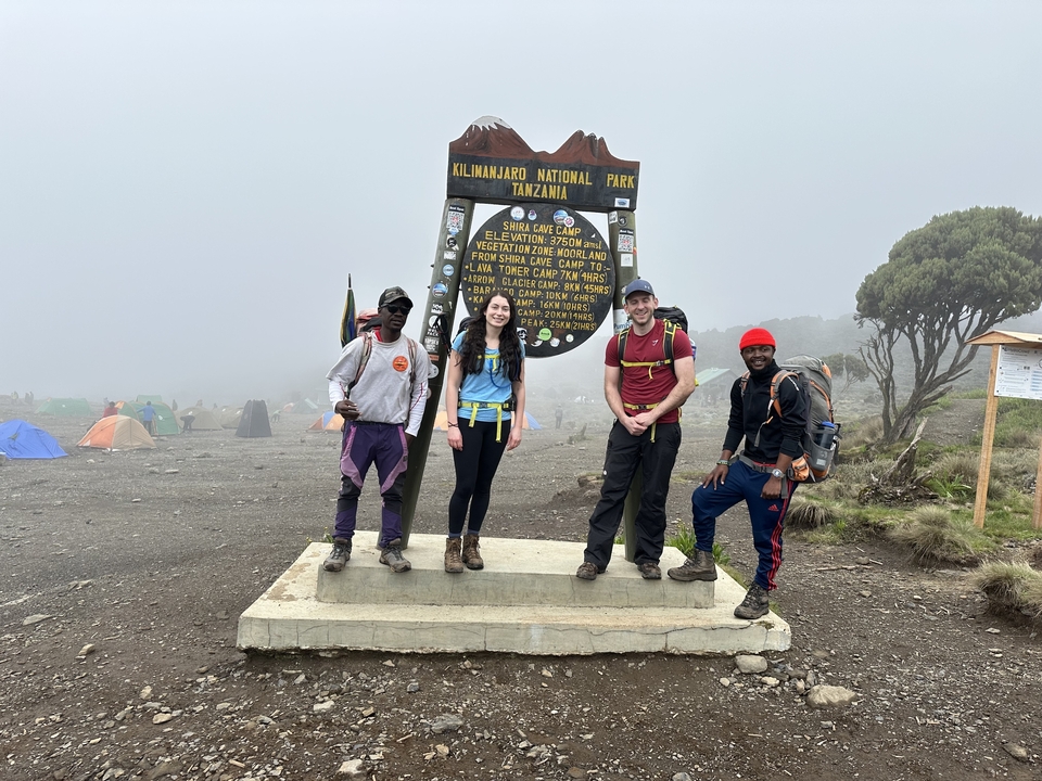 Groupe de randonneurs souriants devant le panneau indicateur du Kilimandjaro.