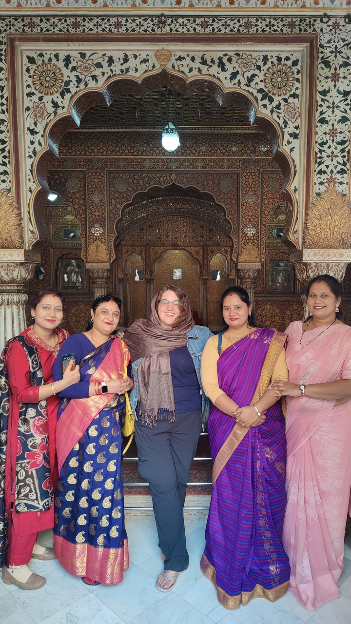 Photo de groupe de femmes en saris traditionnels colorés à l'intérieur d'un bâtiment historique.