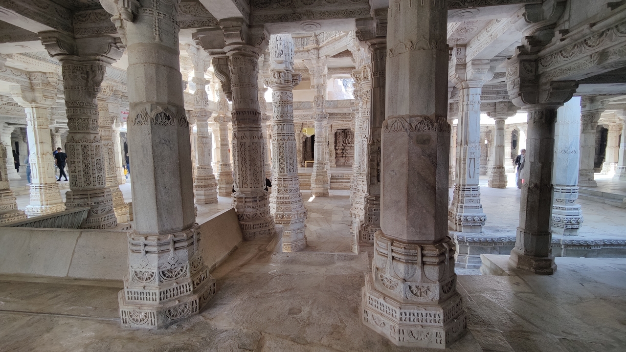 Colonnes finement sculptées et sol en marbre dans un temple indien.