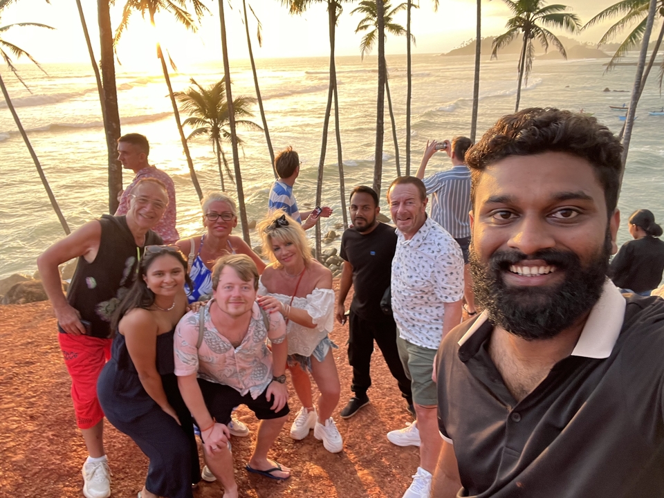 Groupe de personnes prenant un selfie au bord d'une falaise avec vue sur la mer.