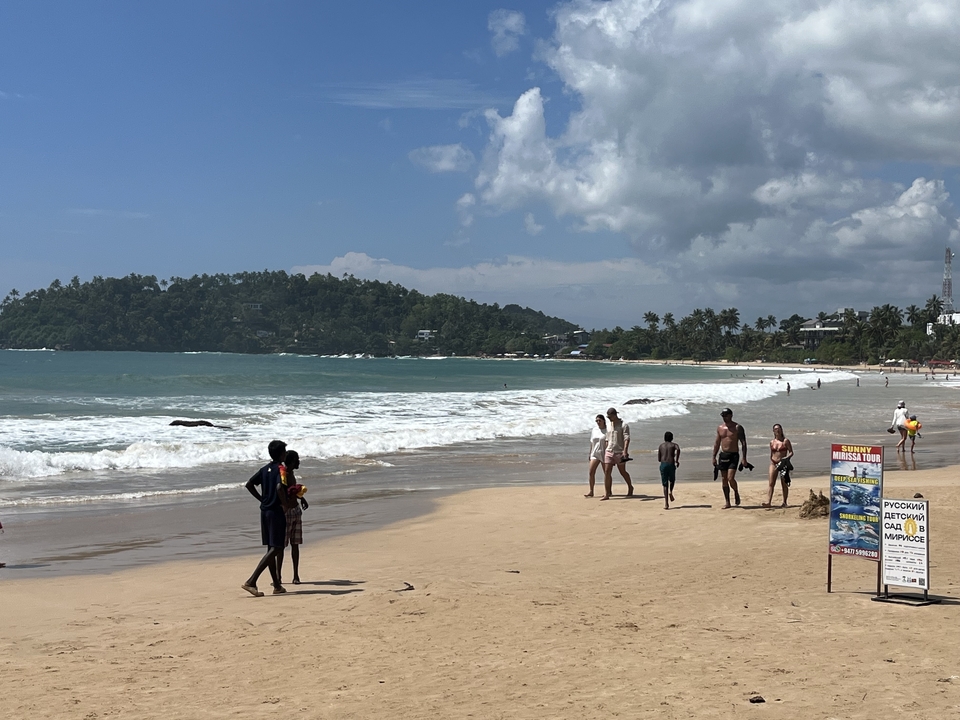 Scène de plage avec des personnes se promenant le long du rivage.